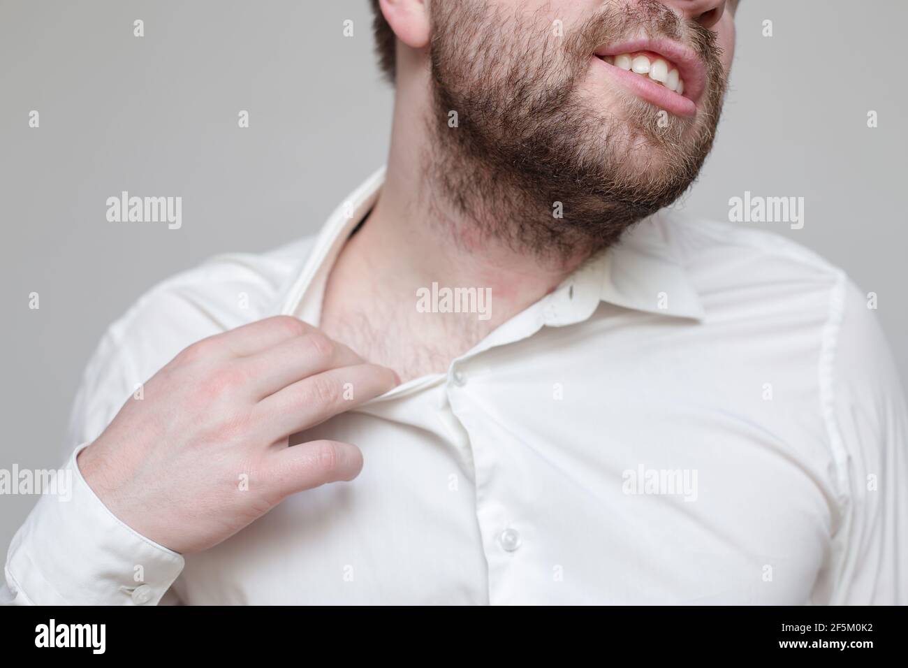 L'uomo bearded non si sente bene, soffoca e cerca di allargare il collare della sua camicia. Foto Stock