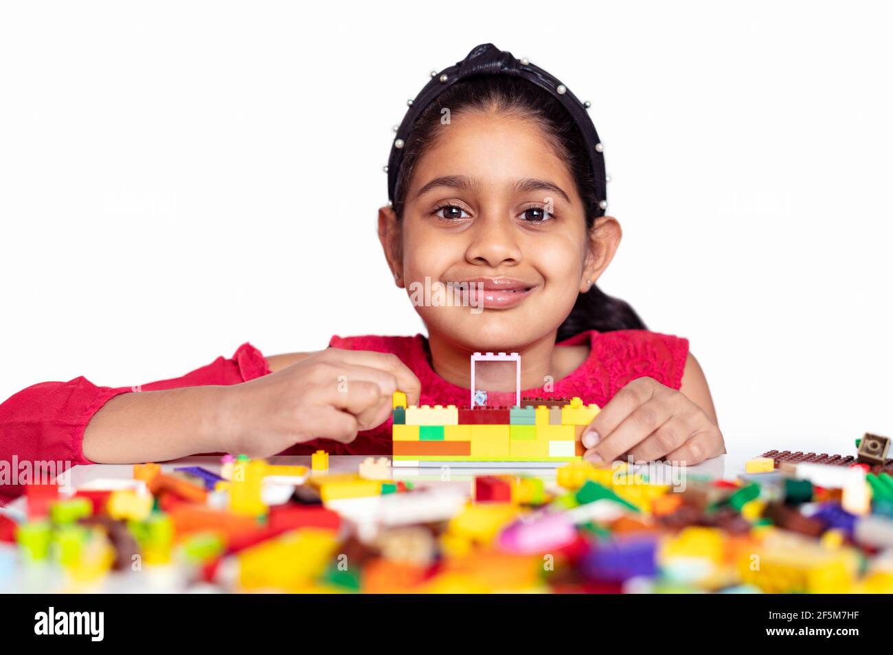 Una bambina indiana carina che gioca con colorati blocchi da costruzione giocattolo e divertirsi. Concetto di attività di sviluppo dei bambini. Apprendimento della scuola precoce Foto Stock