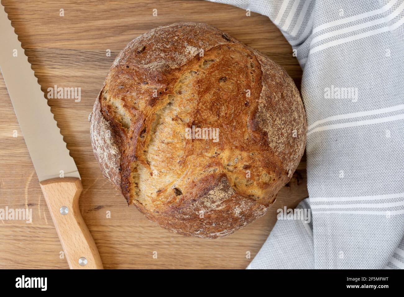 Pane tradizionale appena sfornato e coltello da taglio sul tagliere. Primo piano sul cibo. Foto Stock