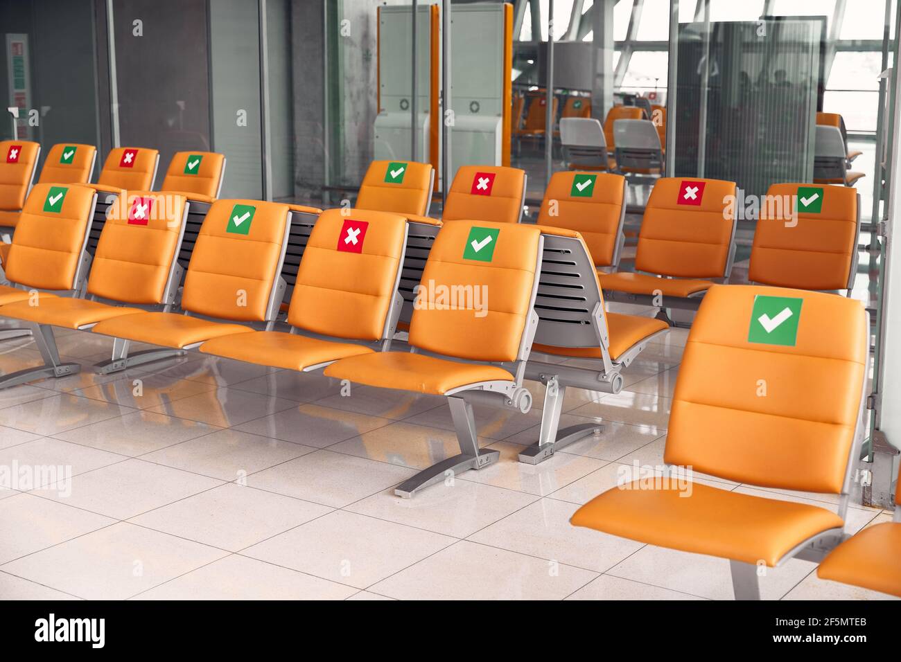 File sedie arancioni vuote che indicano dove è possibile sedersi per mantenere una distanza. Viaggio sicuro nuovo normale Foto Stock