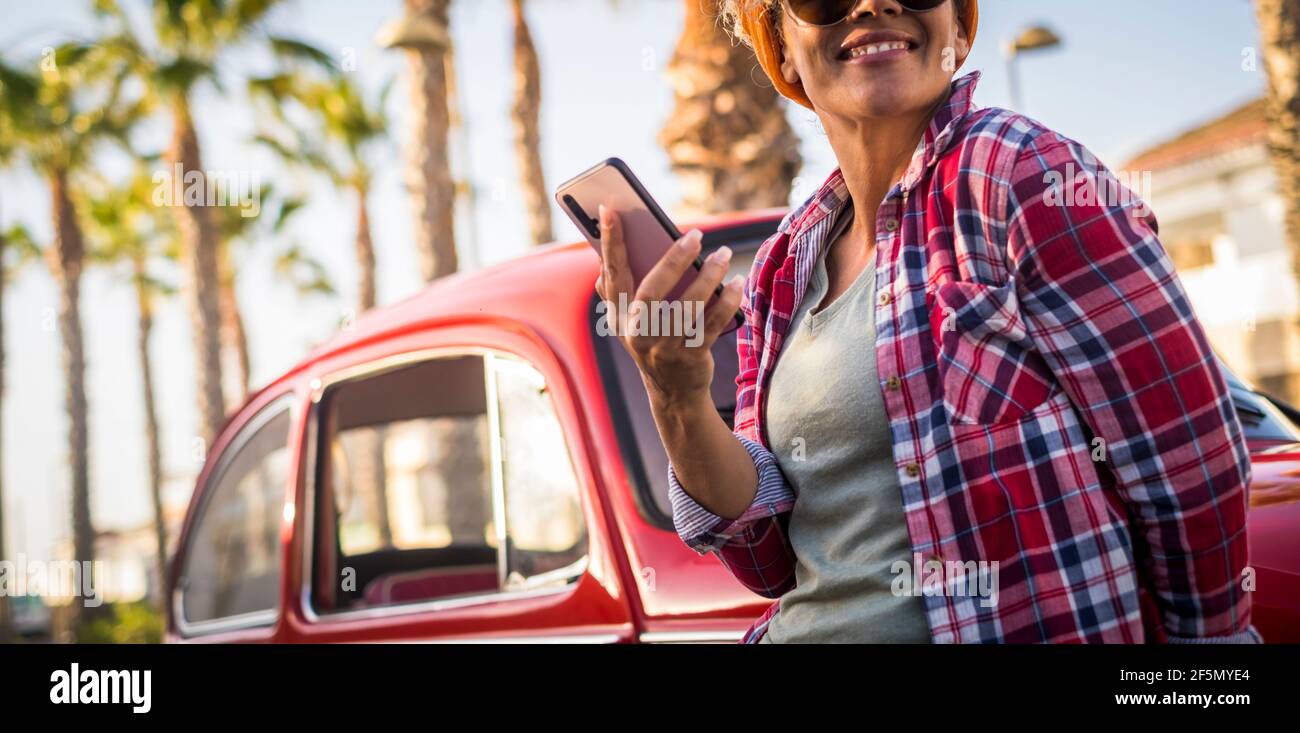 I colori vintage filtrano il vecchio stile del film bello ritratto della donna usando telefona all'esterno dell'auto rossa godendo dello stile di vita di un giorno e di un viaggio - persone alla moda e su Foto Stock