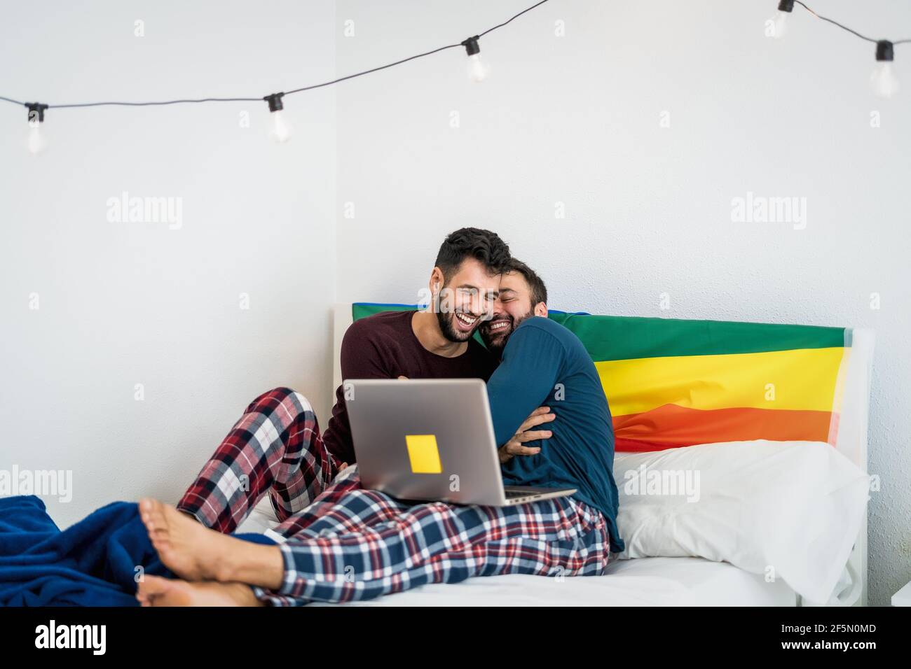 Felice coppia gay divertirsi mentendo con il computer portatile a letto - l'amore omosessuale e l'uguaglianza di genere nel concetto di relazione Foto Stock