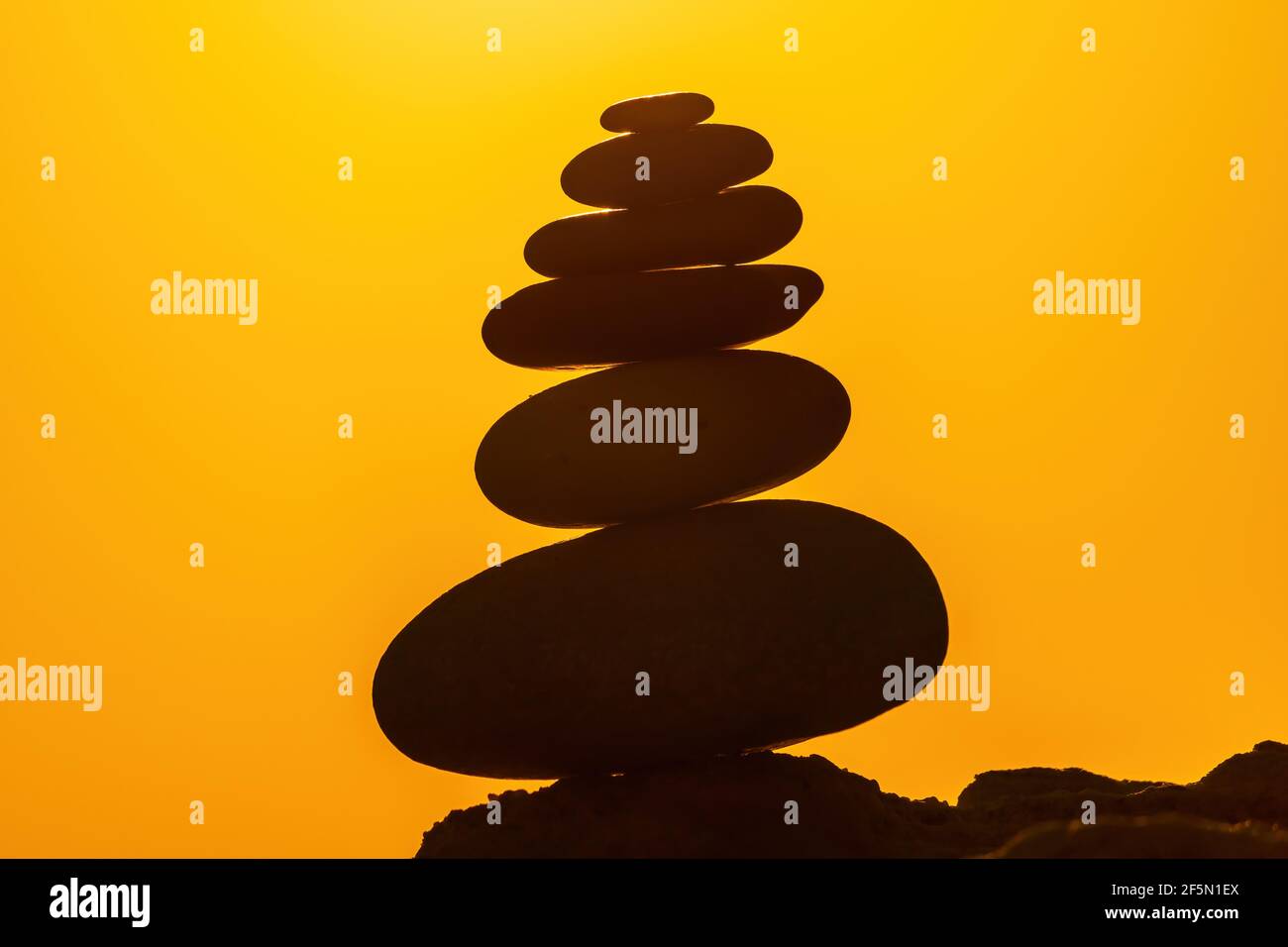 Profilo a piramide di ciottoli bilanciato sulla spiaggia. Astratto caldo tramonto bokeh con Mare sullo sfondo. Pietre Zen sulla spiaggia di mare, meditazione, spa Foto Stock