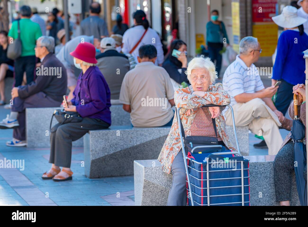 Persone di varie nazionalità sedute su grandi posti a sedere in granito su un occupato Sabato mattina in Freedom Plaza, Cabramatta, Sydney, Australia Foto Stock