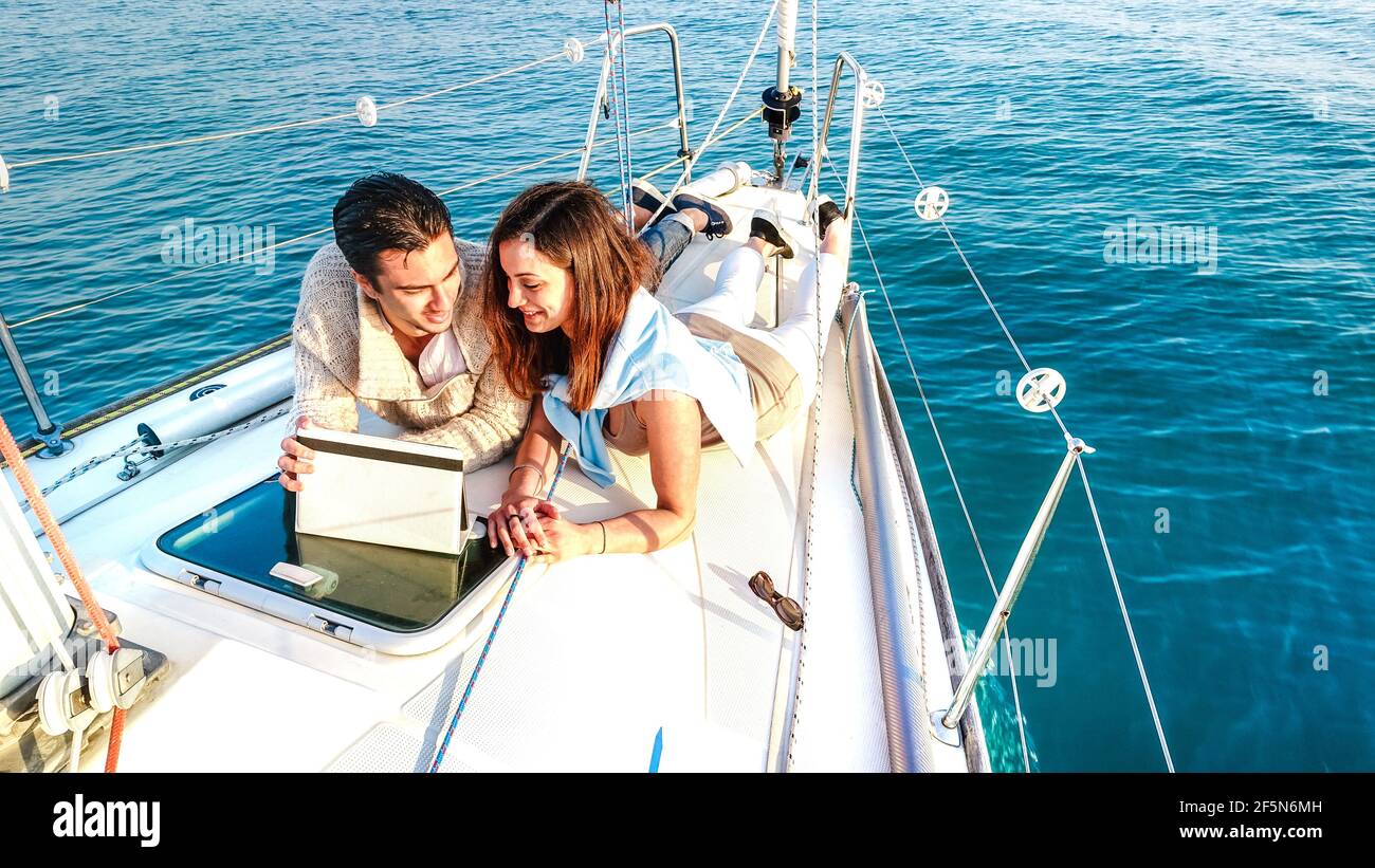 Giovane coppia innamorato divertirsi con il tablet pc barca a vela - stile di vita da viaggio di lusso e concetto nomade digitale su esclusivo tour in yacht Foto Stock