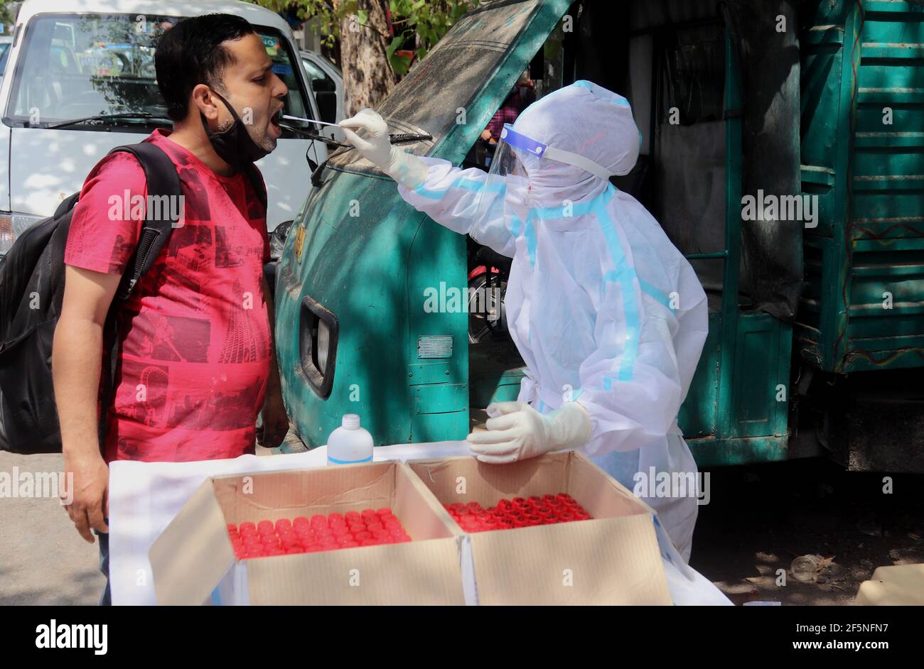 Un operatore sanitario che indossa dispositivi di protezione individuale (DPI) raccoglie campioni di tampone da un uomo per il test di RT-PCR Covid-19 alla strada a Nuova Delhi.Top funzionari delle Nazioni Unite, compreso il capo di mantenimento della pace delle Nazioni Unite, ha espresso gratitudine all'India per il suo dono di 200,000 dosi di vaccino COVID 19 per il mantenimento della pace. L'India ha registrato 62,258 nuove infezioni da coronavirus in 24 ore, il più alto aumento giornaliero finora quest'anno. Secondo ICMR, sono stati analizzati 23,97,69,553 campioni fino al 26 marzo 2021, con 11,64,915 campioni testati il venerdì. Foto Stock