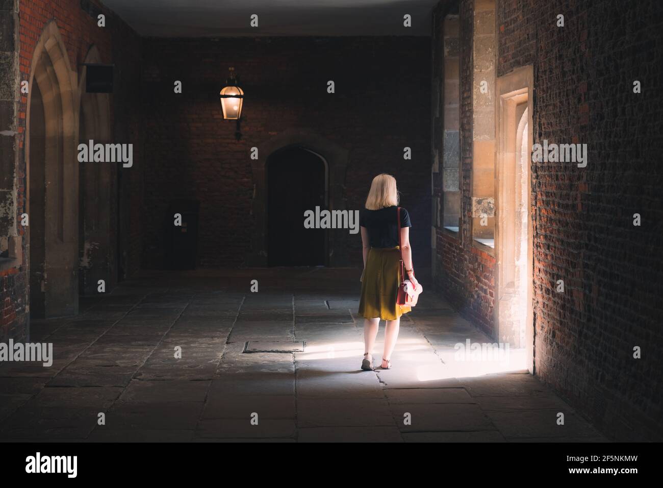 Molesey, UK - UNA giovane ragazza bionda turistica visita gli interni storici della residenza reale del 16 ° secolo Hampton Court Palace con luce naturale del sole. Foto Stock