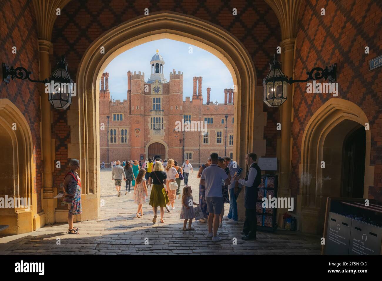 Molesey, Regno Unito - i turisti affollano l'ingresso ad arco alla storica residenza reale del XVI secolo, l'Hampton Court Palace e il cortile in una giornata estiva. Foto Stock