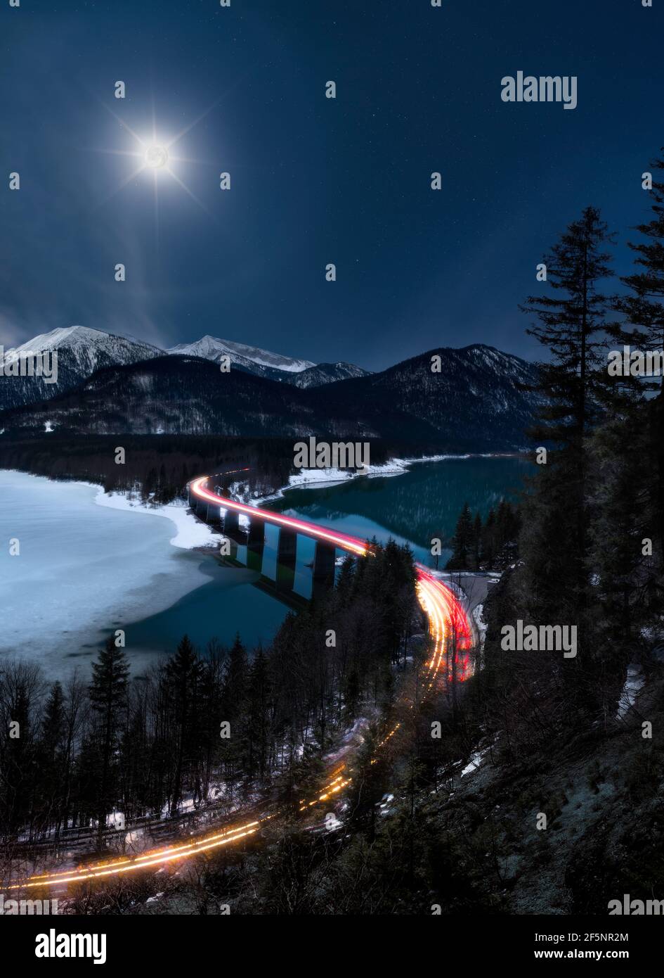 Strada nella montagna di notte - luna piena con alone che illumina la scena Foto Stock