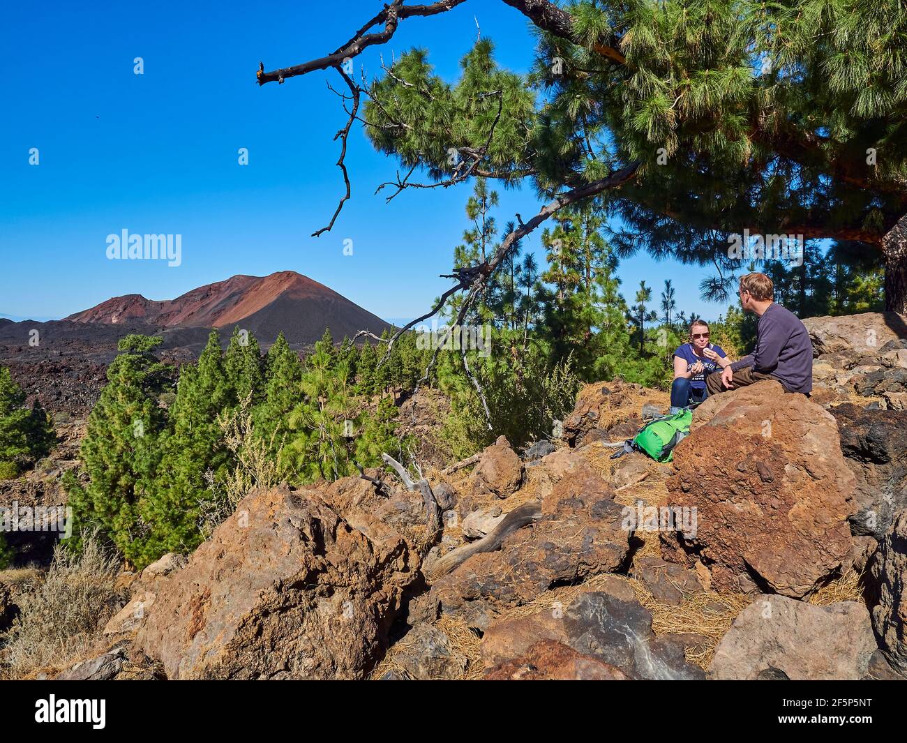 giovane coppia caucasica con un cazzo di scelta in un'escursione intorno al vulcano el teide sull'isola delle canarie di tenerife, seduto sulle rocce laviche in una bella Foto Stock