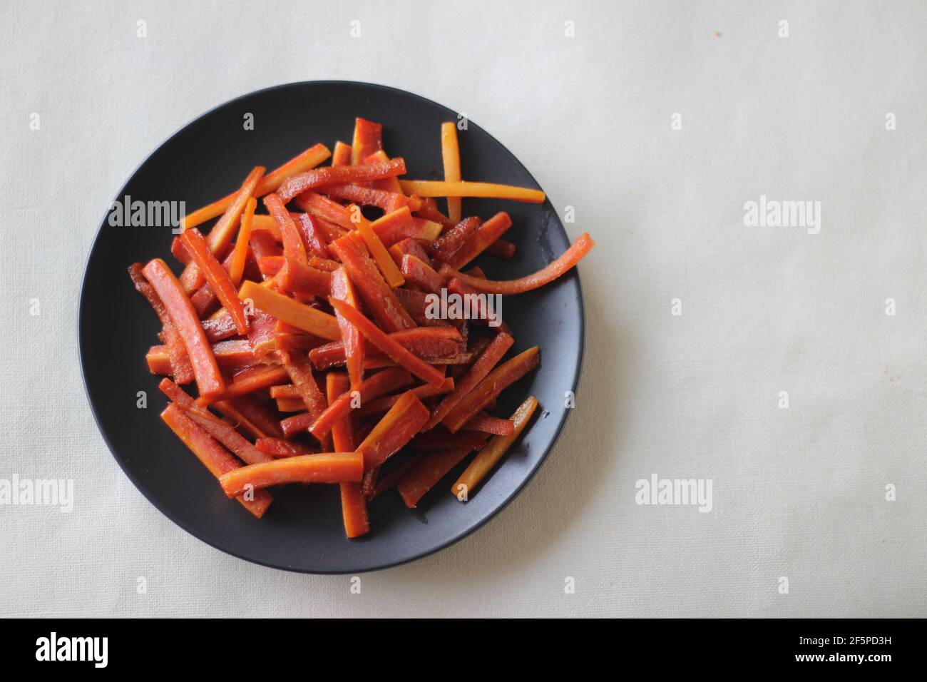 Bastoncini di carote caramellate. Carote salate con burro e zucchero. Uno spuntino veloce e sano. Scatto su sfondo bianco Foto Stock