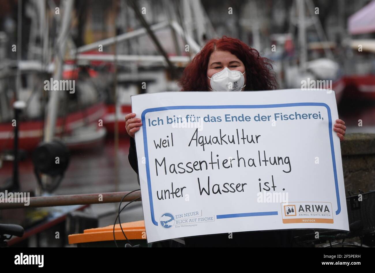 Rostock, Germania. 27 Marzo 2021. In occasione di una dimostrazione "un nuovo sguardo al pesce", un partecipante porta un poster con la scritta "sono per la fine della pesca, perché l'acquacoltura è un'azienda agricola in acqua". L'azione ha avuto luogo nell'ambito della campagna mondiale della V Giornata mondiale per la fine della pesca. Gruppi locali dell'organizzazione per i diritti degli animali Animal Rights Watch (ARIWA) avevano chiesto l'azione. I contromandanti di Warnemünde hanno chiesto su un poster 'il pesce Baltico su ogni tavolo'. Secondo la polizia, la manifestazione è rimasta pacifica. Foto: Stefan SA Credit: dpa Picture Alliance/al Foto Stock