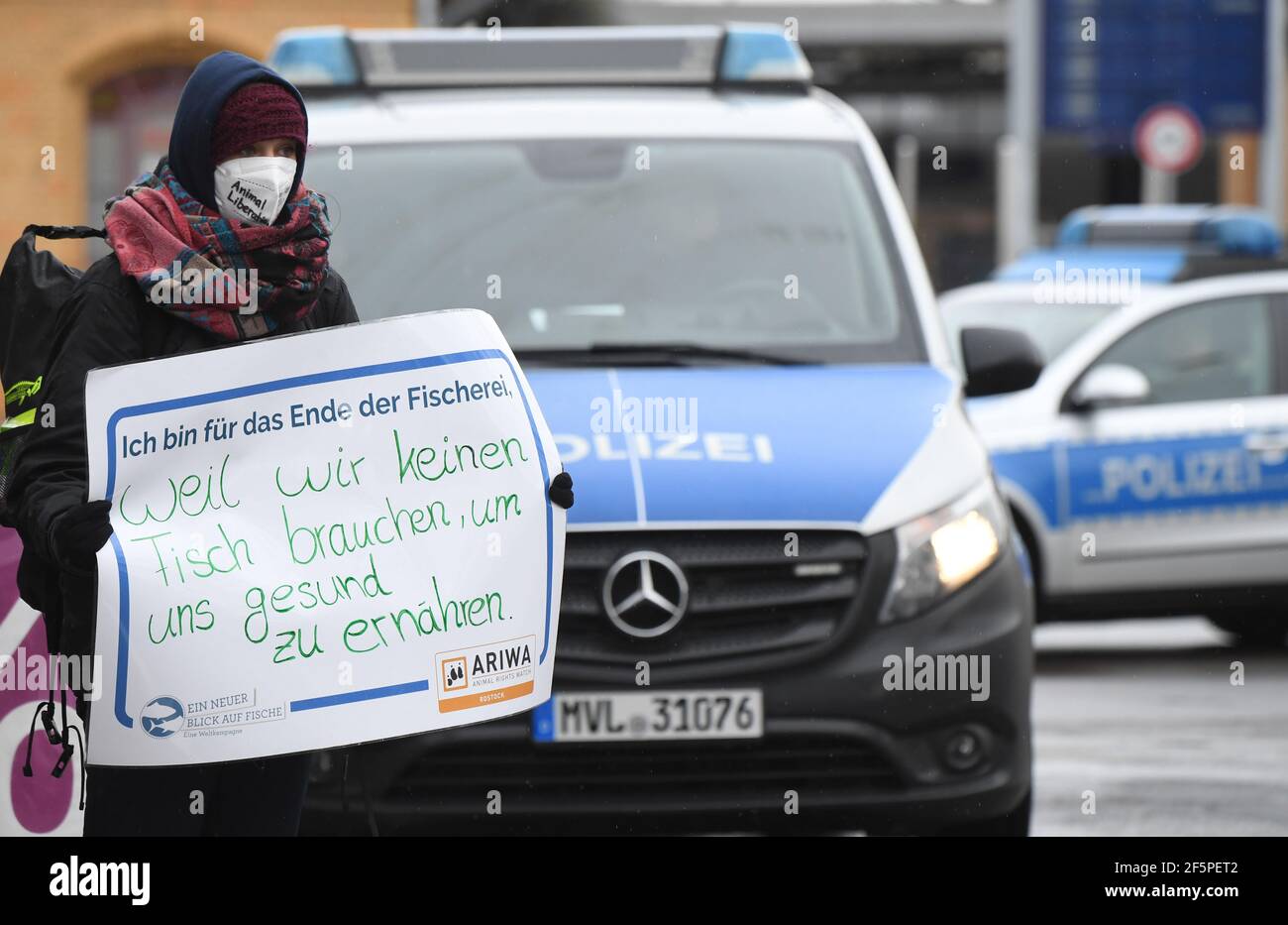 Rostock, Germania. 27 Marzo 2021. Su una dimostrazione "UN nuovo sguardo al pesce" un partecipante porta un poster con la scritta "sono per la fine della pesca, perché non abbiamo bisogno di pesce per nutrirci sani. L'azione ha avuto luogo nell'ambito della campagna mondiale della 5a Giornata mondiale per la fine del Fishing.called, in cui si sono svolte le associazioni locali dell'organizzazione per la protezione degli animali Animal Rights Watch (ARIWA).i contromandanti di Warnemünde hanno chiesto su un poster 'il pesce Baltico su ogni tavolo'.secondo la polizia, la manifestazione è rimasta pacifica. Foto: Stefan SA Credit: dpa Picture Alliance/al Foto Stock