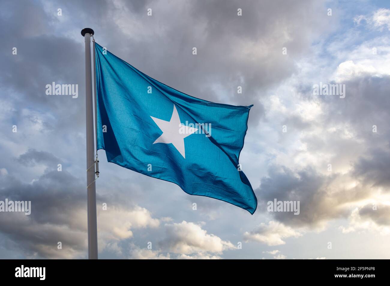 Simbolo di Somalia. Bandiera nazionale somala su un palo che oscilla sullo sfondo del cielo nuvoloso. Foto Stock