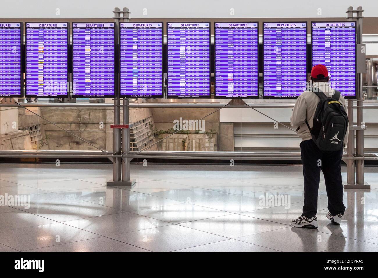 Denver, Colorado - UN viaggiatore guarda il bordo di partenza all'aeroporto internazionale di Denver. I viaggi sono aumentati con la speranza degli americani che il coronav Foto Stock