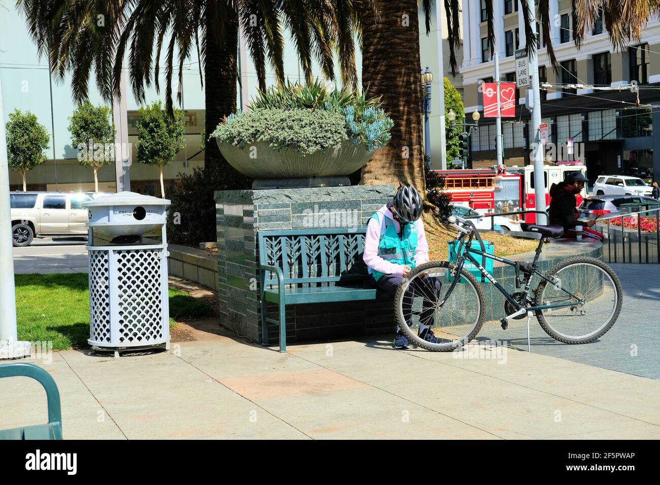 Rider for Fantuan, Asian Food Delivery, che fa una pausa in panchina nel centro di San Francisco, California; Fantuan è stato fondato a Vancouver, Canada nel 2014. Foto Stock