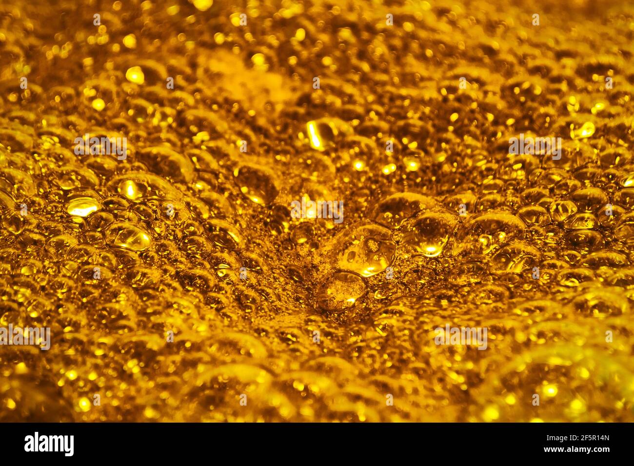 Oro bollente. La consistenza della schiuma come sfondo. Concetto di sfondo e texture. Primo piano di schiuma dorata gorgogliante Foto Stock