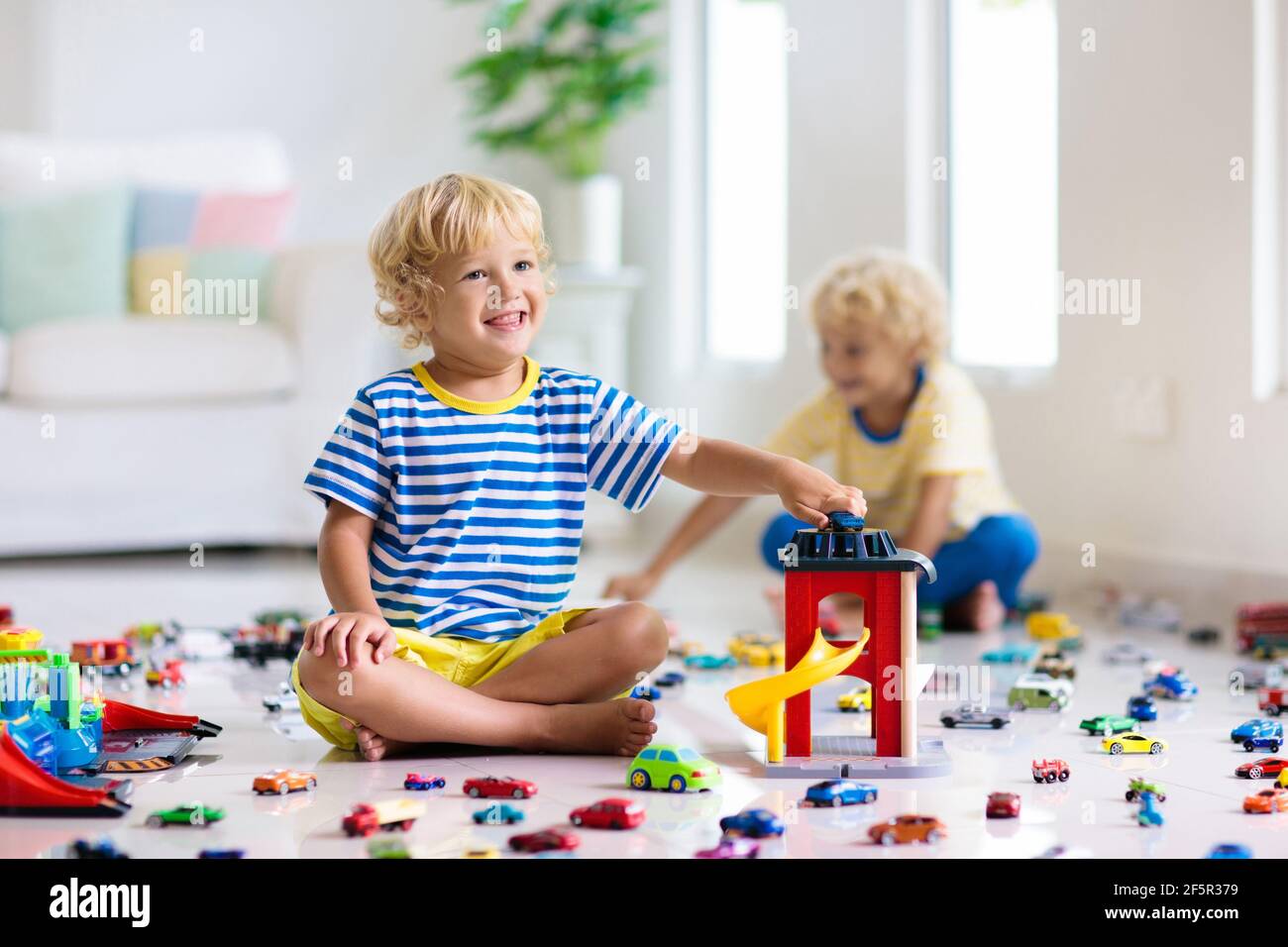 I bambini giocano con macchinine giocattolo nella stanza bianca. Bambino  che gioca con auto e camion giocattoli. Veicolo e gioco di trasporto per  bambini Foto stock - Alamy