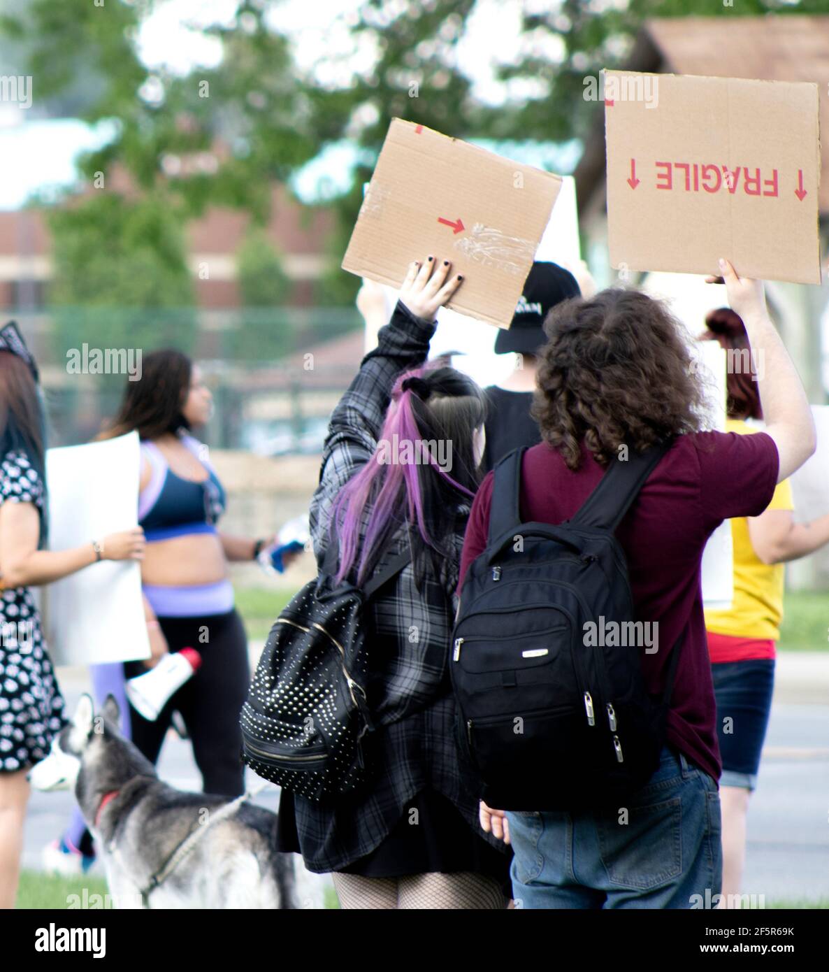 Giovani che partecipano a una protesta silenziosa e pacifica lungo la strada con cartelli e manifesti di cartone Foto Stock