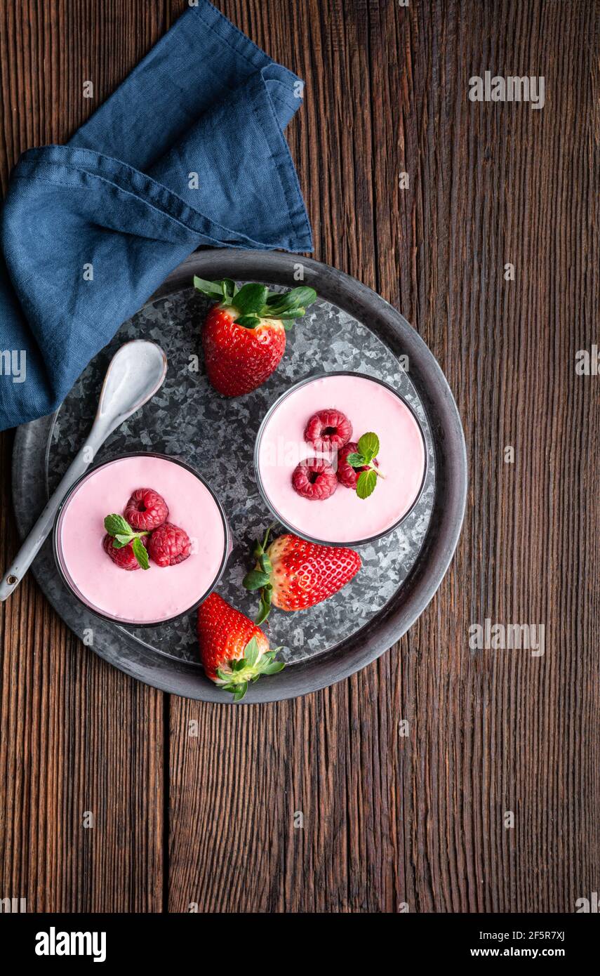 Bevanda sana, frullato di fragola e lampone con yogurt greco in un vaso di vetro su rustico sfondo di legno Foto Stock