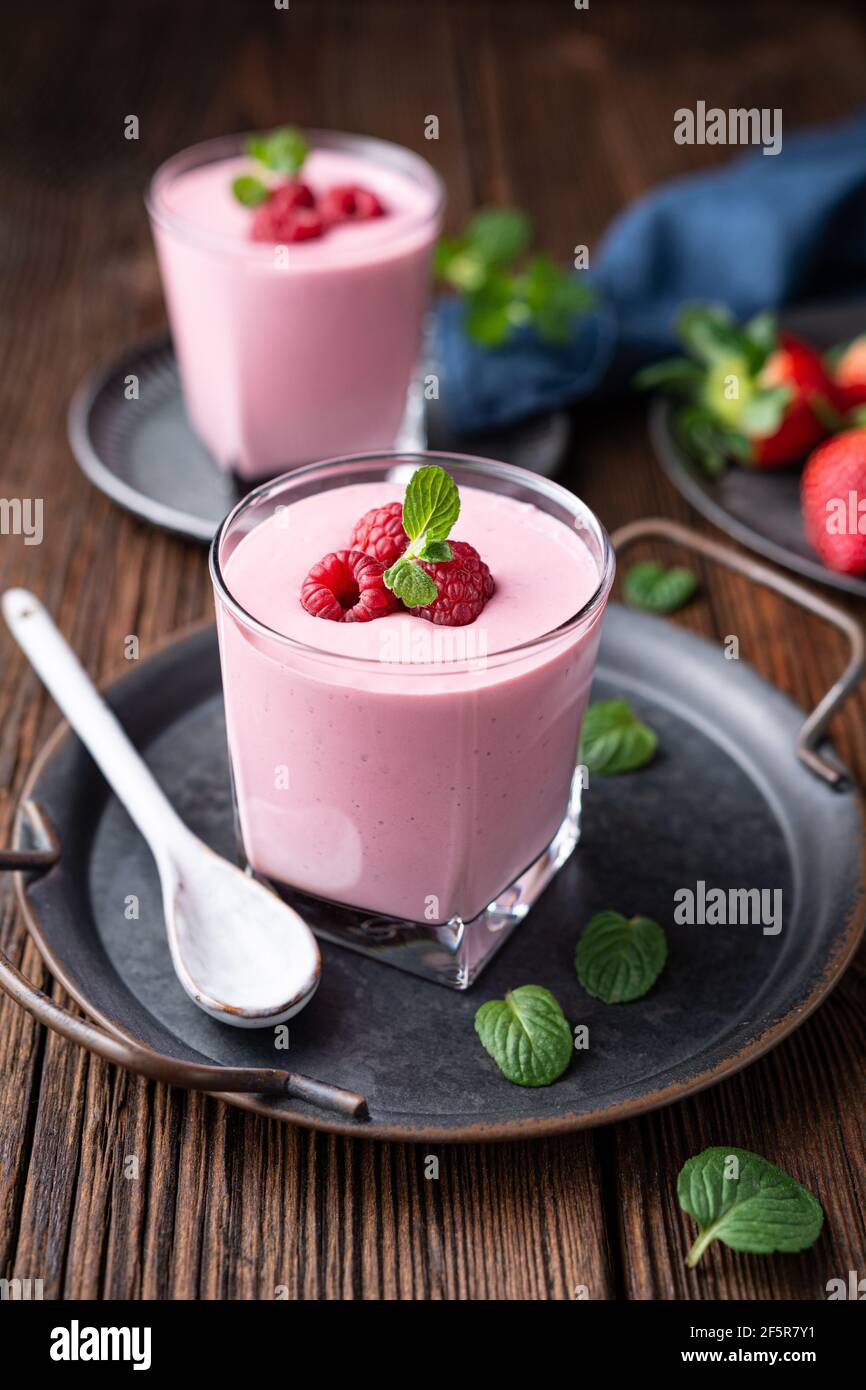 Bevanda sana, frullato di fragola e lampone con yogurt greco in un vaso di vetro su rustico sfondo di legno Foto Stock