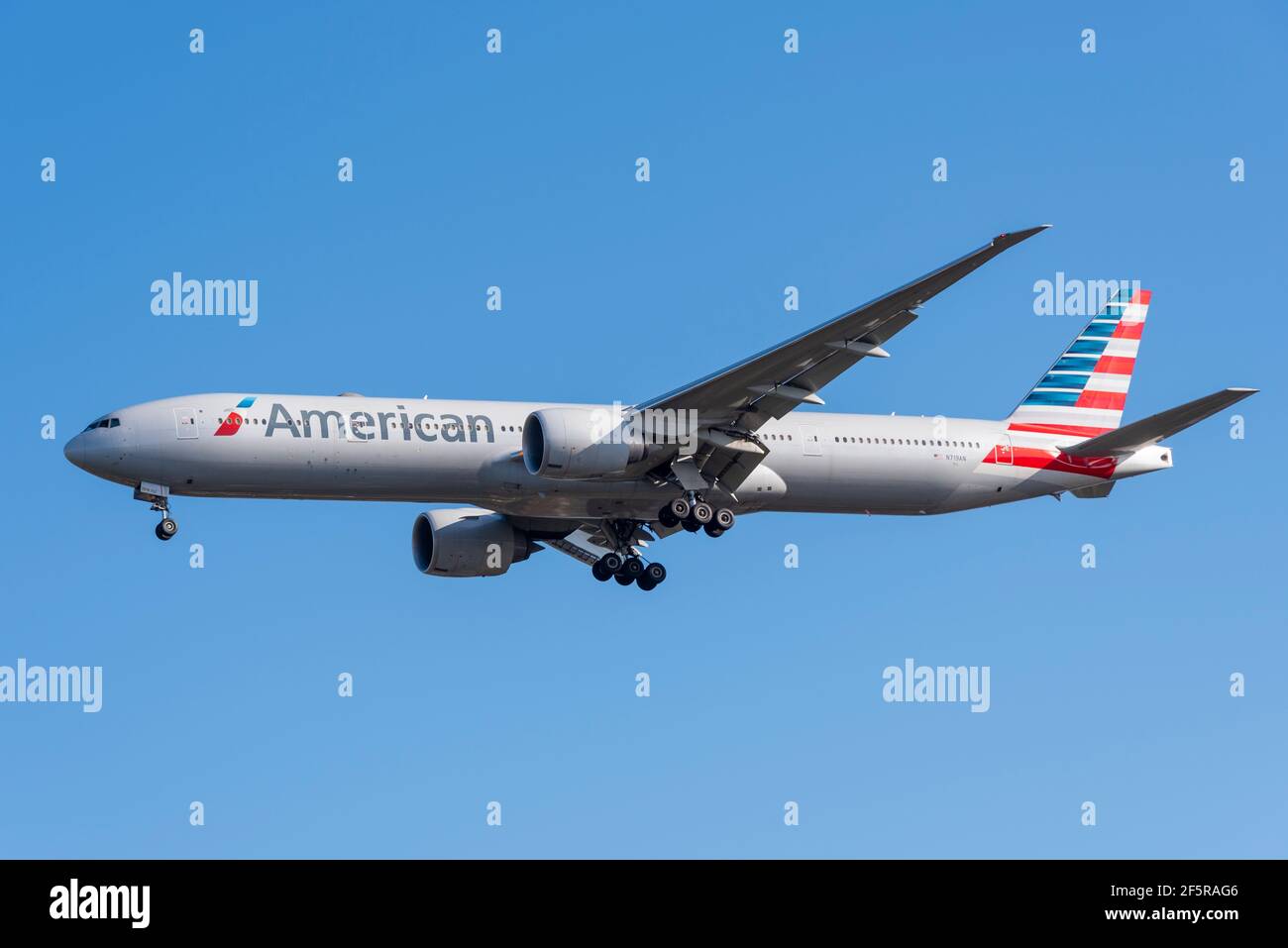 American Airlines Boeing 777 300 ER aereo jet N719AN a portata estesa sulle finali per atterrare all'aeroporto Heathrow di Londra, Regno Unito, in cielo blu. Laterale Foto Stock