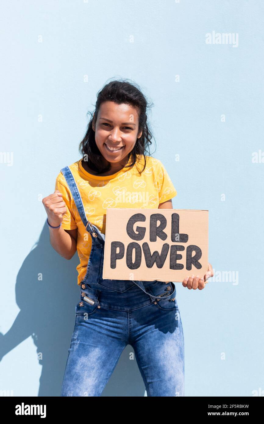 Ritratto di una donna latina che tiene un banner con lo slogan Girl Power. È isolata su sfondo blu. Foto Stock