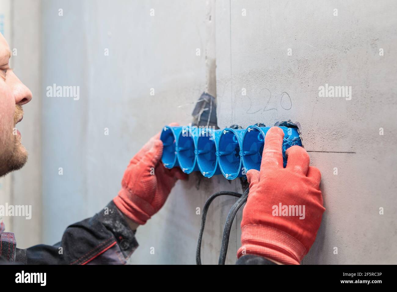 L'elettricista inserisce la scatola di plastica direttamente nei fori di uscita. Primo piano Foto Stock