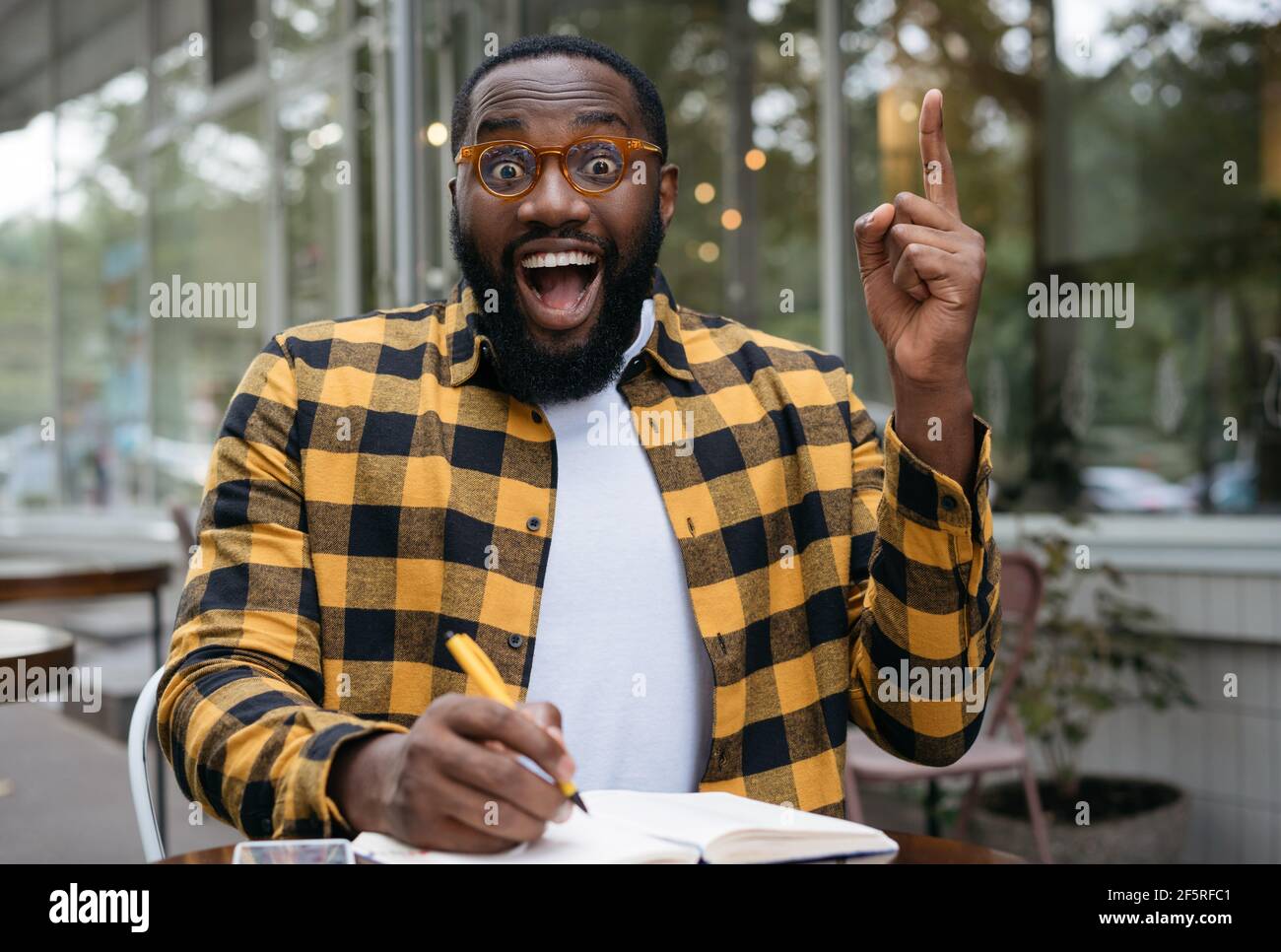 Ritratto dello studente impressionabile afroamericano che studia, impara la lingua, tiene il dito in su, ha idea creativa Foto Stock