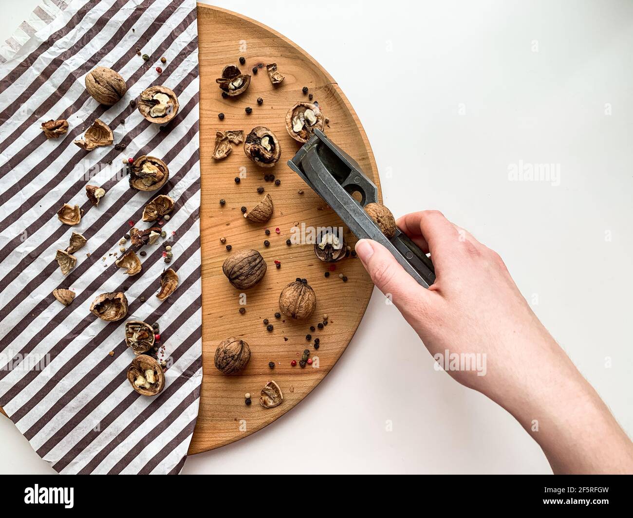 Donna che cagna noci su una tavola di legno, bianco copia spazio sfondo. Foto Stock