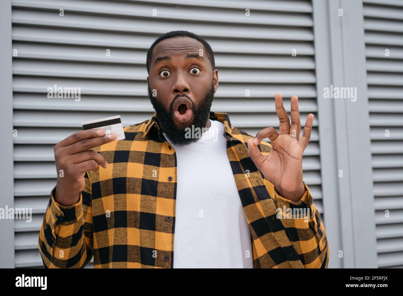 Eccitato afroamericano uomo tenendo carta di credito per lo shopping online,  mostrando segno OH Foto stock - Alamy