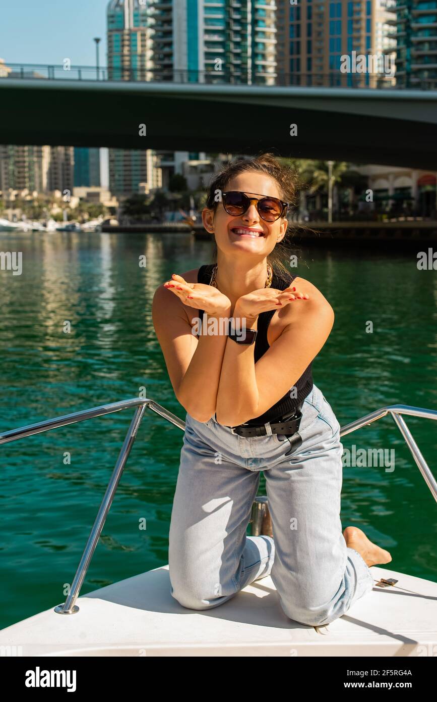 donna soleggiata che manda baci d'aria sorridente e godendo la vita in barca Foto Stock