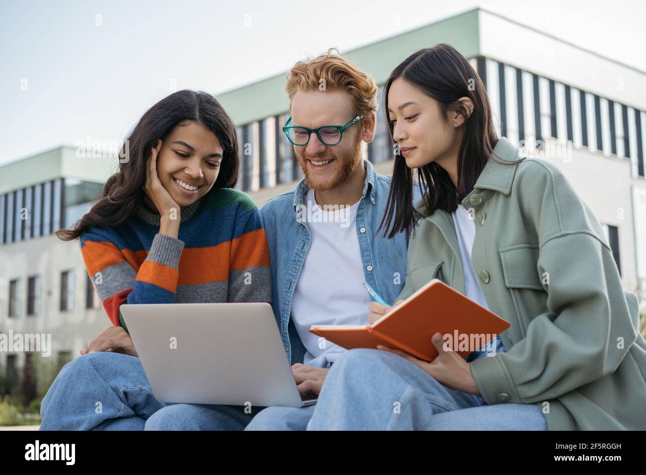 Gruppo di studenti universitari multirazziali che utilizzano il laptop, lo studio, la preparazione degli esami, il concetto di istruzione. Giovani colleghi sorridenti che si riunono, lavorando online Foto Stock