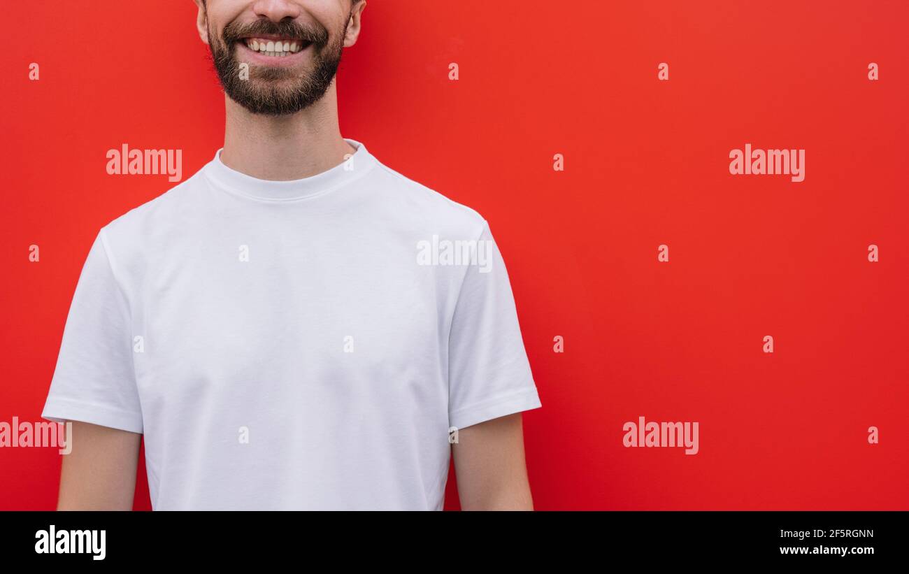 Modello giovane e bello che indossa una t-shirt casual isolata su sfondo rosso, mock-up. Immagine ritagliata di un uomo elegante bearded sorridente Foto Stock