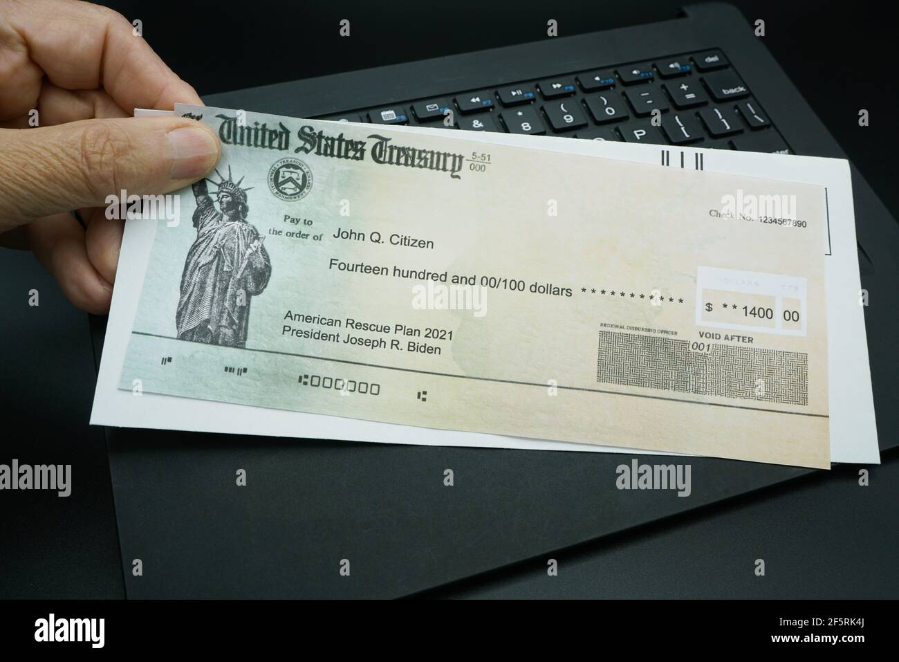 Mans Hand detiene un assegno illustrativo del Tesoro degli Stati Uniti per illustrare il pagamento dell'American Rescue Plan Act del 2021. Foto Stock