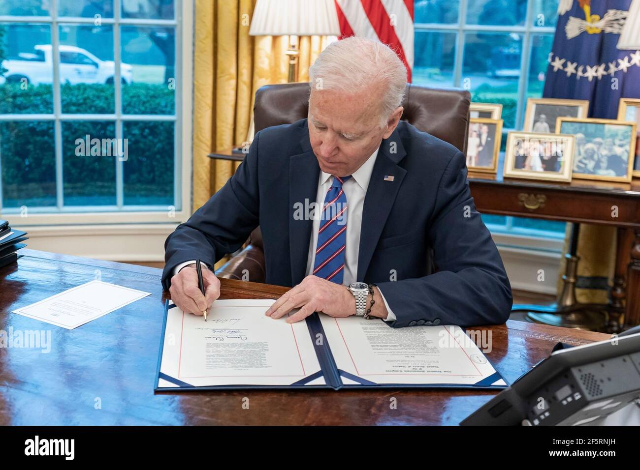 Il presidente degli Stati Uniti Joe Biden firma il Save Lives Act in legge durante una cerimonia nell'Ufficio ovale della Casa Bianca 25 marzo 2021 a Washington, D.C. la legge consente all'Amministrazione dei Veterani di fornire vaccinazioni COVID-19 a tutti i veterani, i loro coniugi e gli operatori sanitari. Foto Stock