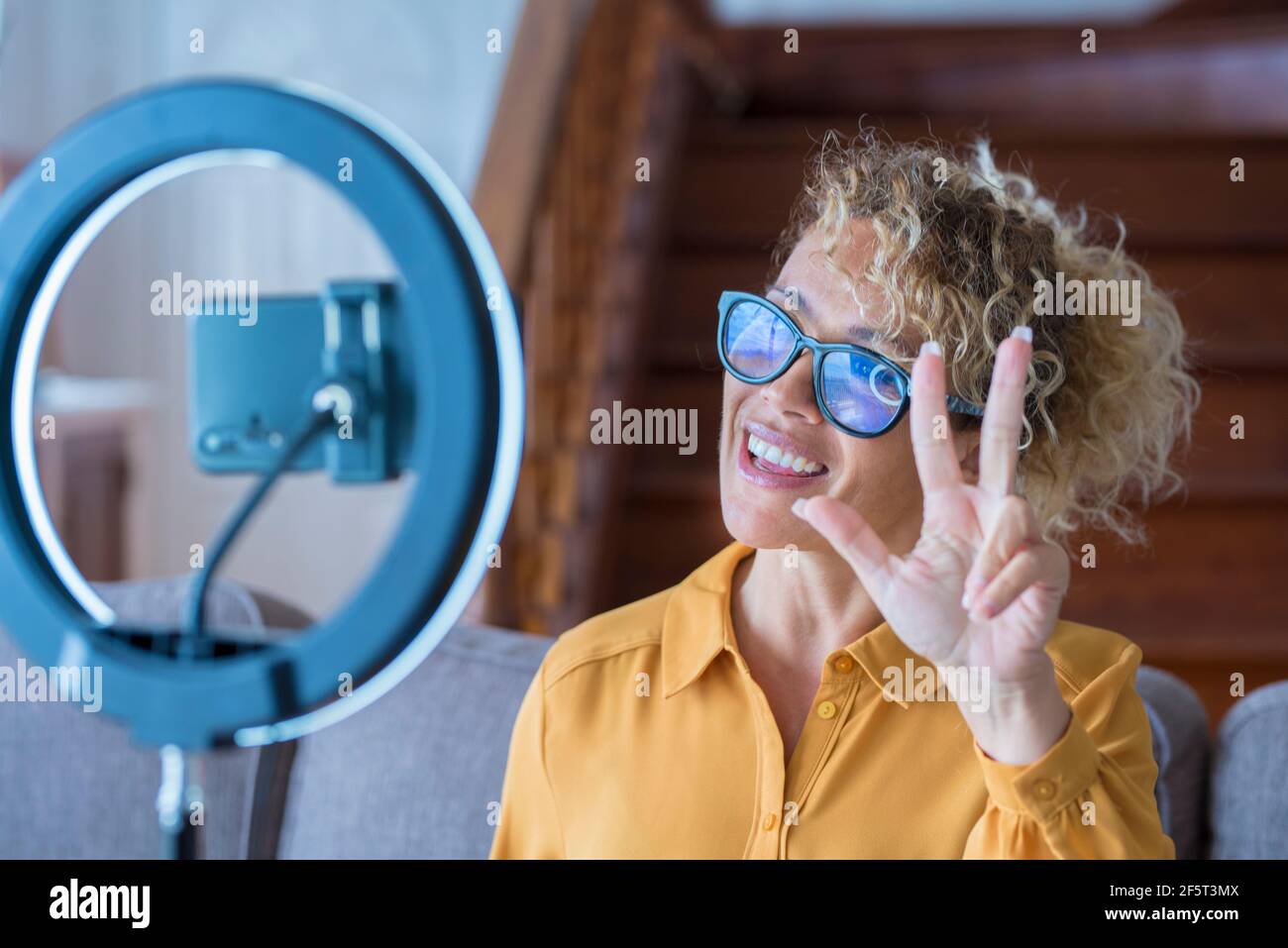 Ritratto di bella donna adulta che parla di fronte a telefono per registrare contenuti online - concetto di casa moderna lavoro e creatore digitale - videochiamata Foto Stock