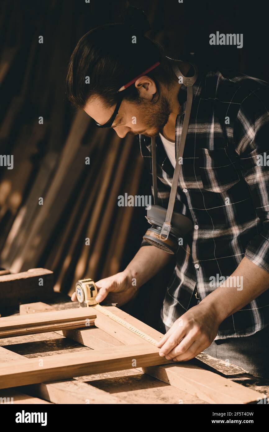 Falegname uomo cura di fare opere in legno capolavoro mobili artigianali misura fine in legno officina, verticale colpo. Foto Stock