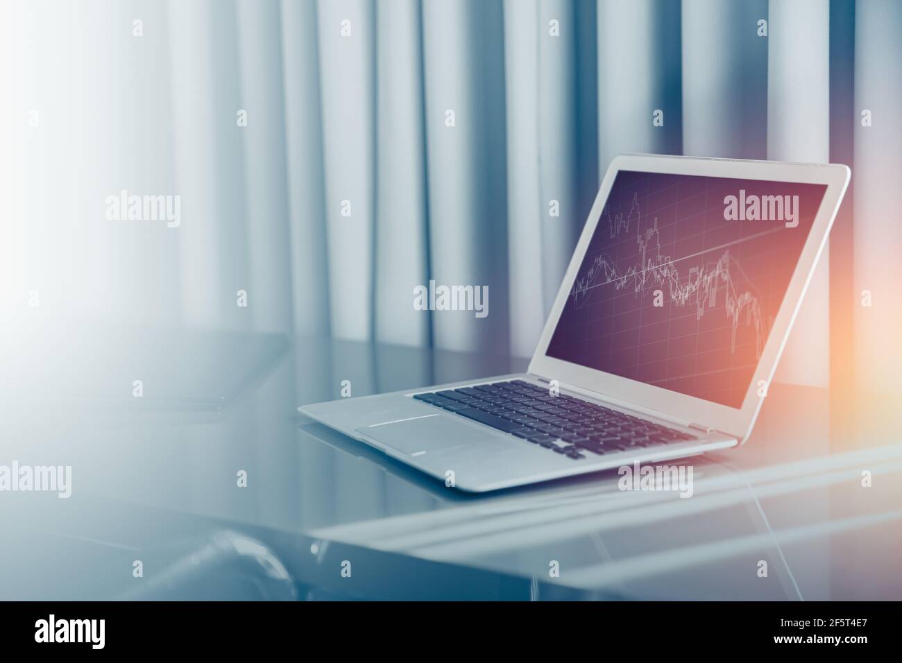 Computer portatile sulla scrivania dell'ufficio con cartografia blu tono di colore per il denaro background aziendale. Foto Stock