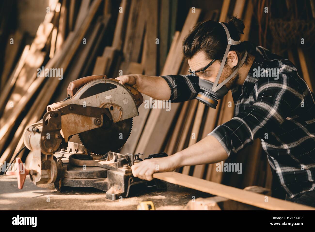 Falegname uomo che usa la taglierina elettrica per legno con sicurezza di protezione attrezzature in officina in legno Foto Stock