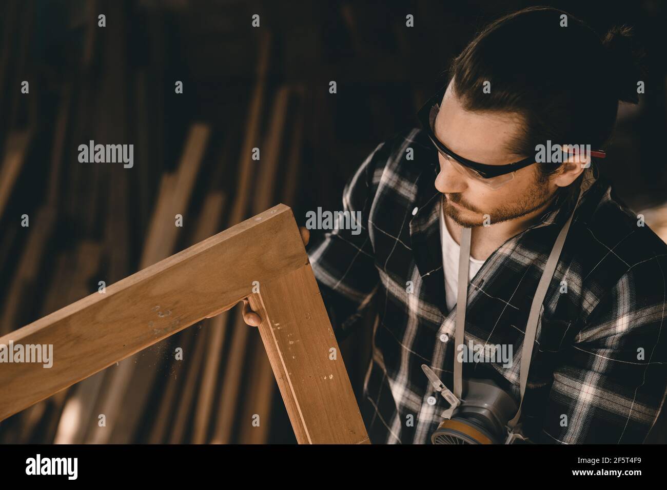 Falegname uomo professionista esperto in legno lavoro cercando dettaglio di artigianato in legno capolavoro in officina di mobili Foto Stock