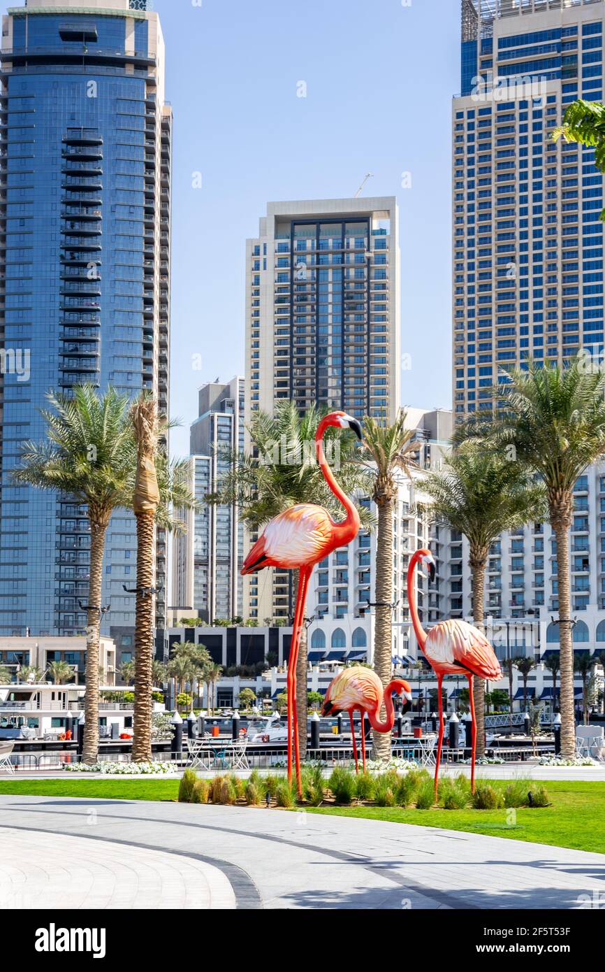 Dubai, Emirati Arabi Uniti, 22.02.2021. Grandi statue di fenicotteri sulla passeggiata del Dubai Creek Harbour con skyline sullo sfondo. Foto Stock