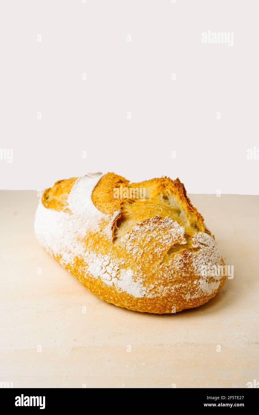 Pane delizioso con farina sulla superficie dorata in panetteria sfondo bianco Foto Stock