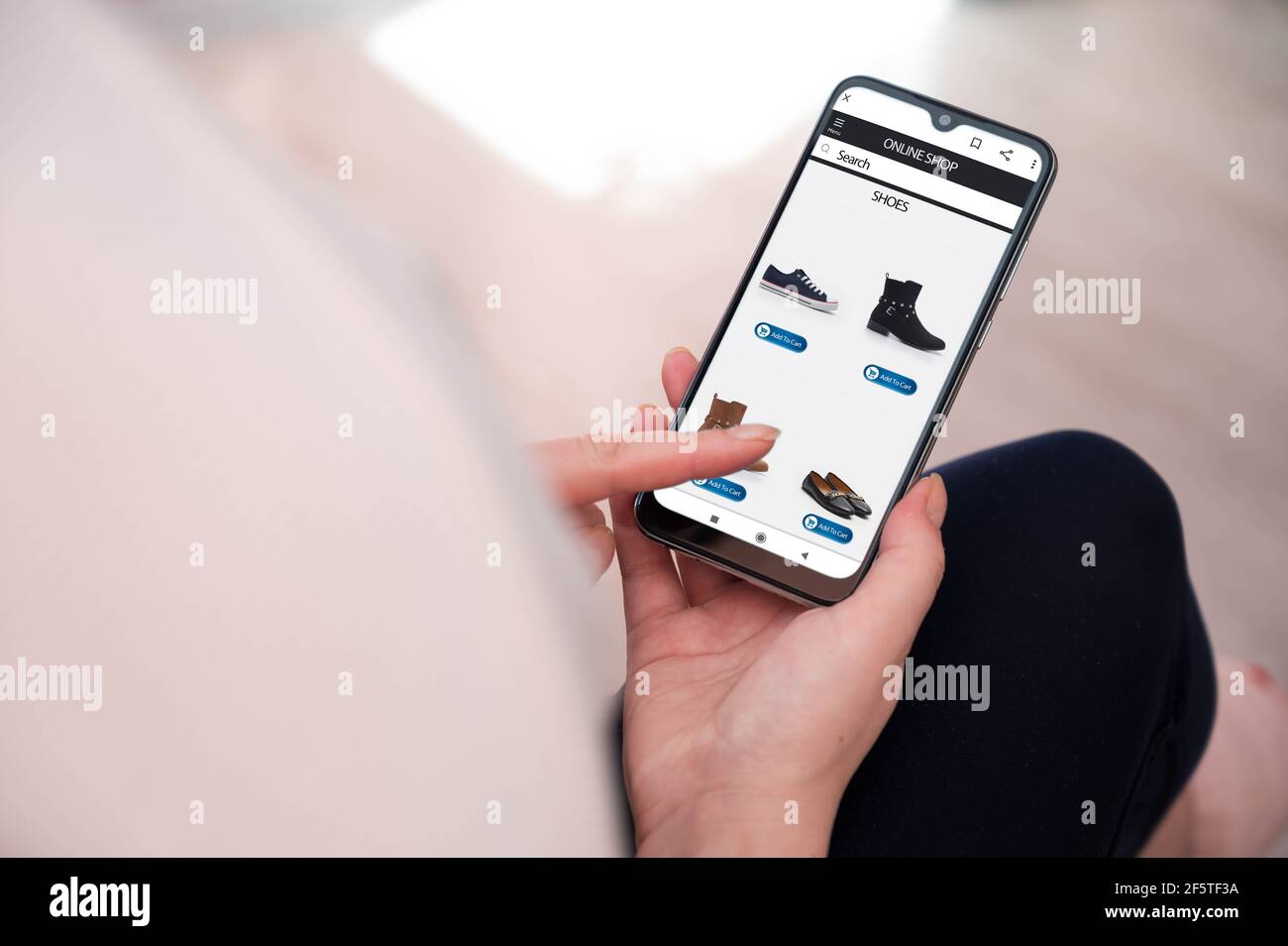 Donna che tiene uno smartphone, che acquista online sul divano a casa. Scatto su spalla. E-commerce , ordine online concetto Foto Stock