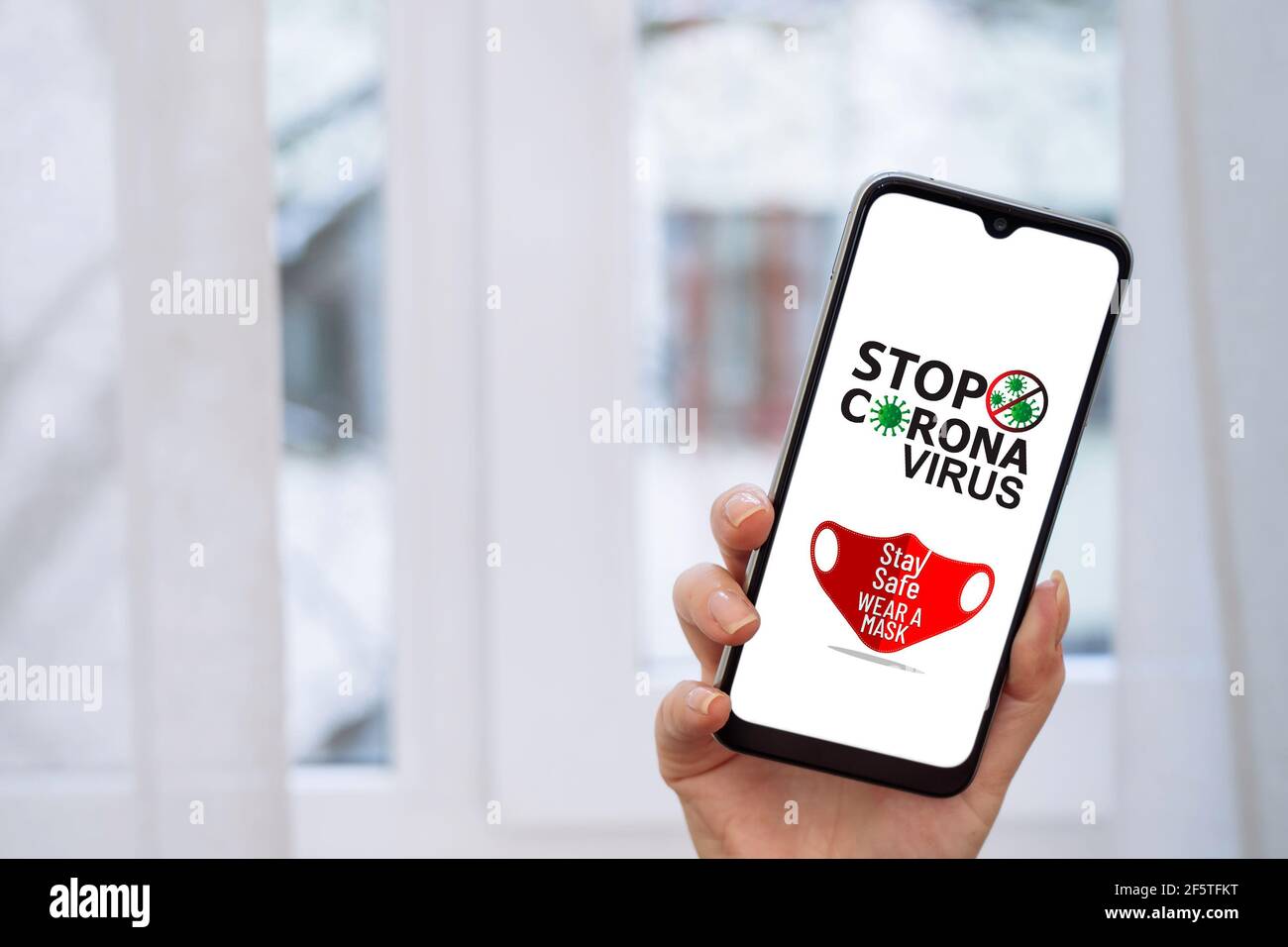 SEGNALE DI ARRESTO coronavirus con maschera rossa sullo schermo dello smartphone. Foto Stock