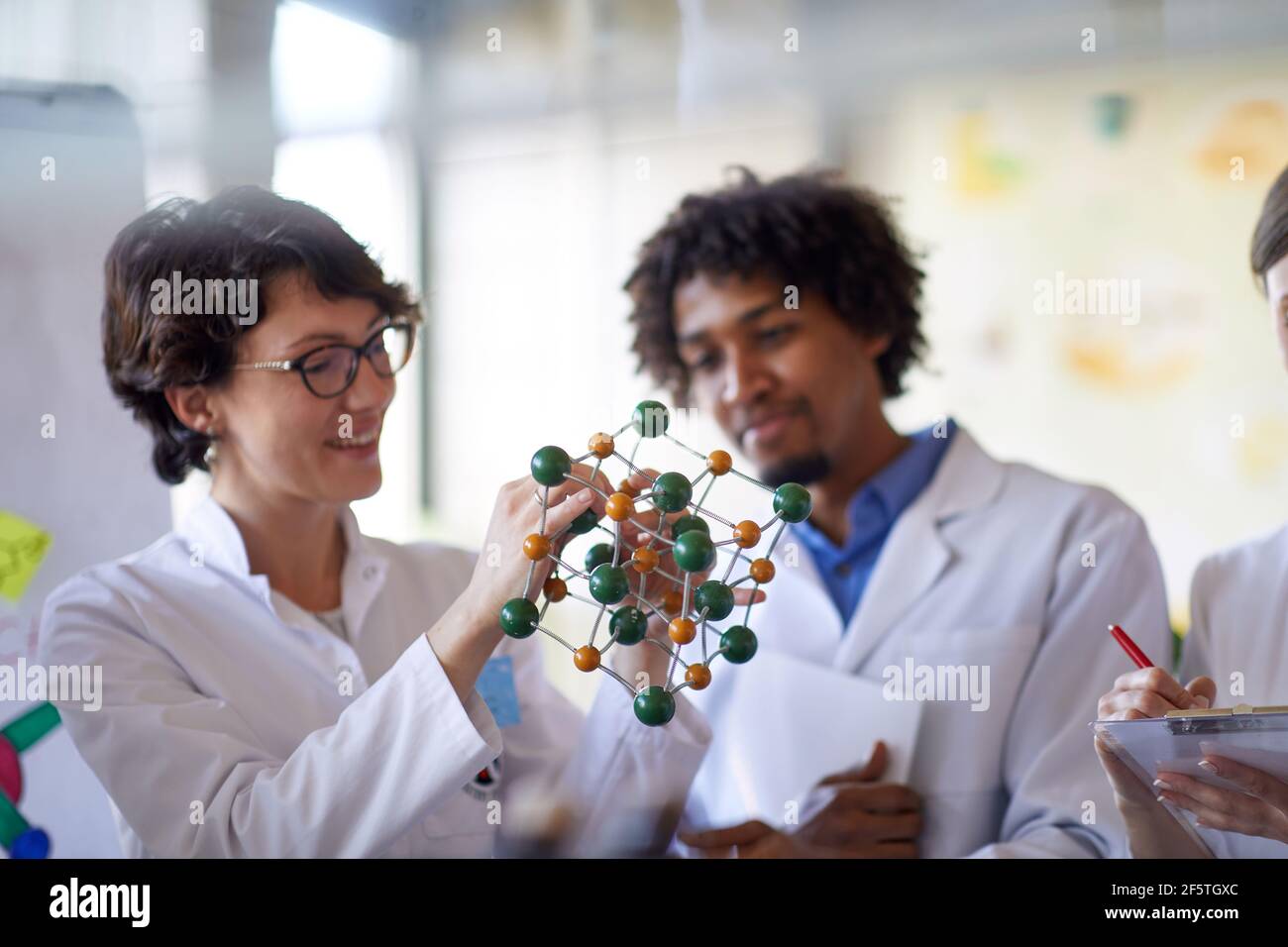 I giovani colleghi imparano a conoscere i legami chimici su un modello in un'atmosfera di lavoro nel laboratorio universitario. Scienza, chimica, laboratorio, persone Foto Stock