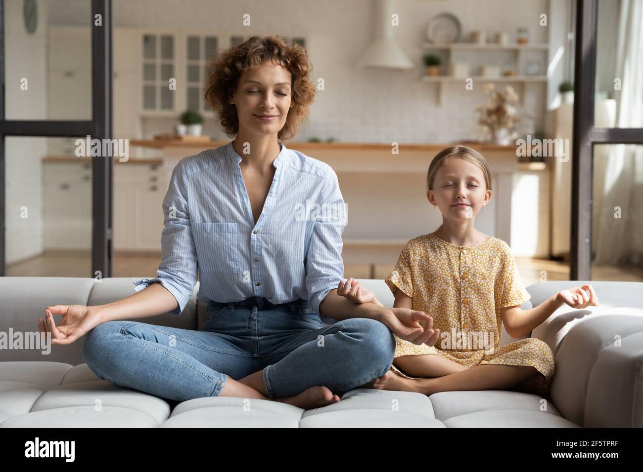Calma giovane mamma e piccola figlia pratica yoga Foto Stock
