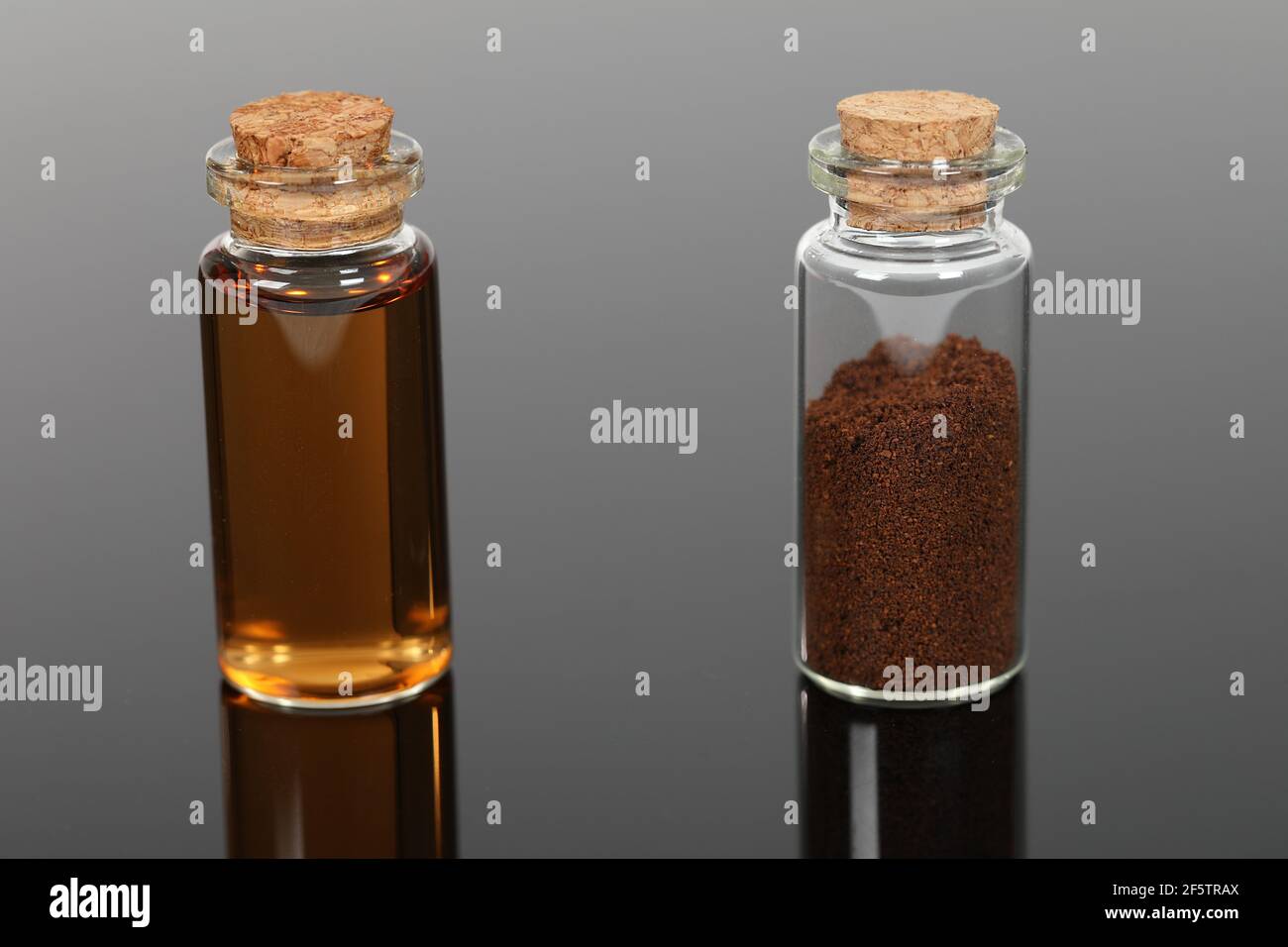 Bottiglie di vetro piccole con polvere marrone e liquido. Foto Stock