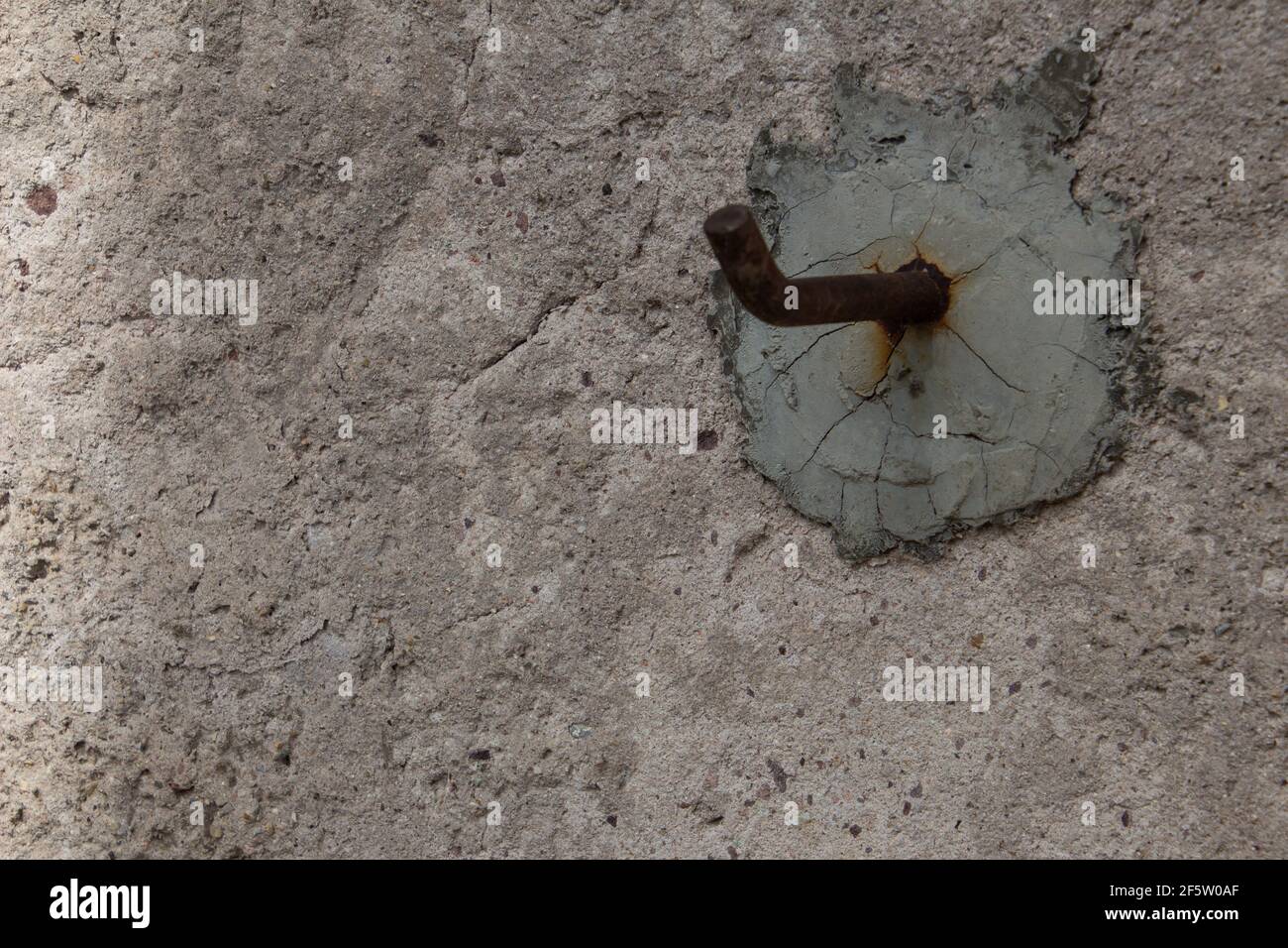 Gancio in metallo arrugginito cementato in una parete Foto Stock