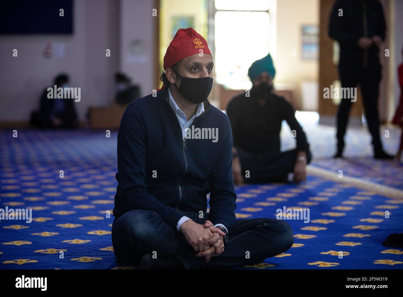 Glasgow, Regno Unito, il 28 marzo 2021. ANAS Sarwar (con copertura rossa), leader del Partito laburista scozzese, visita il Central Gurdwara Glasgow, il primo giorno di servizi per la comunità Sikh da quando le restrizioni di blocco hanno cominciato ad alleggerire. Sarwar stava intraprendendo la visita come parte della campagna elettorale per le elezioni parlamentari scozzesi del 6 maggio. Photo credit: Jeremy Sutton-Hibbert/Alamy Live News Foto Stock